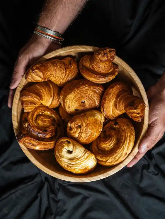 Panier en bois garni de viennoiseries artisanales fraîches, croissants et pains au chocolat par Maison Vivien
