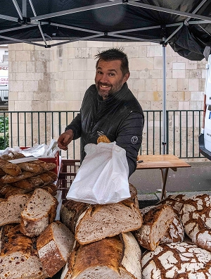 Vivien, artisan boulanger, vous accueille avec le sourire sur son étal de pains au levain lors des marchés caennais